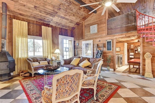 living room featuring wooden ceiling, a wood stove, wood walls, washing machine and dryer, and high vaulted ceiling