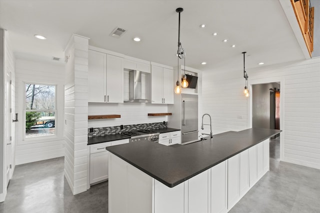 kitchen featuring stainless steel appliances, dark countertops, visible vents, finished concrete floors, and wall chimney exhaust hood