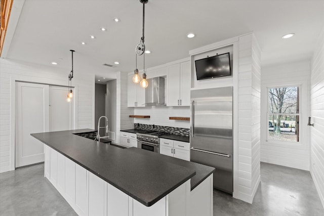 kitchen with premium appliances, a sink, finished concrete flooring, and wall chimney exhaust hood