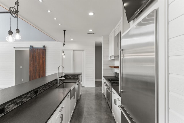 kitchen featuring dark countertops, concrete flooring, a sink, and built in fridge