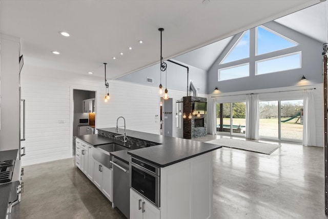 kitchen with dark countertops, open floor plan, a sink, and finished concrete flooring