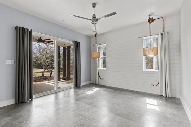 empty room featuring ceiling fan, concrete floors, and plenty of natural light