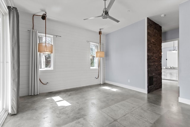 empty room with finished concrete flooring, ceiling fan, and baseboards