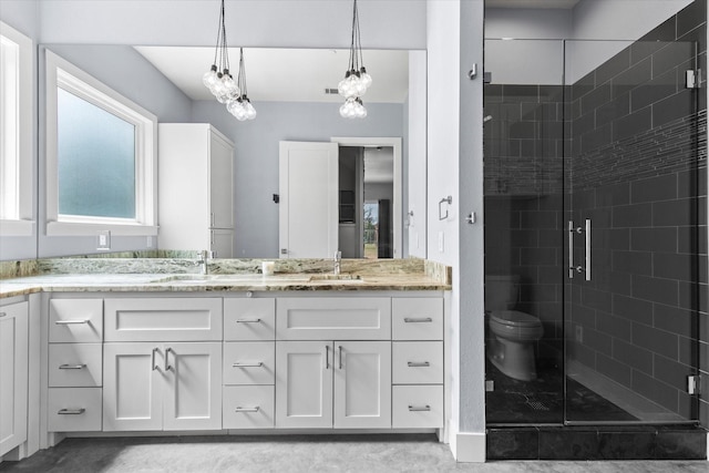 bathroom featuring a sink, a shower stall, toilet, and double vanity