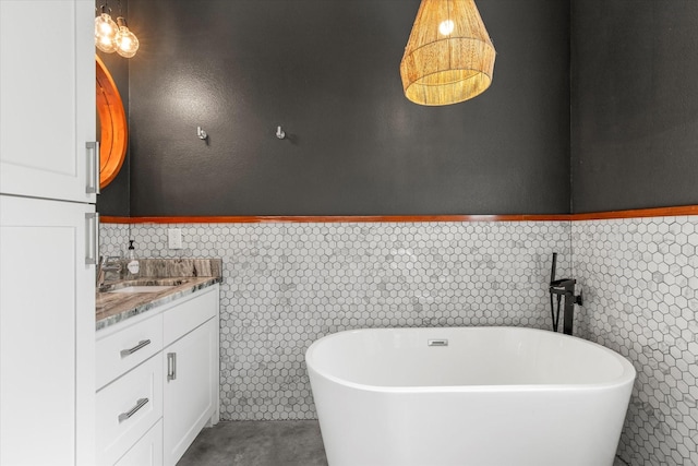 bathroom featuring a freestanding bath, wainscoting, and vanity