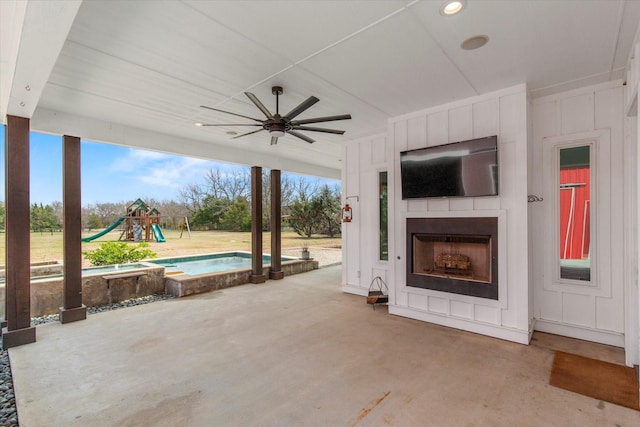 view of patio / terrace featuring a ceiling fan, exterior fireplace, and a playground