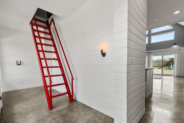 hall featuring finished concrete flooring, a high ceiling, and recessed lighting