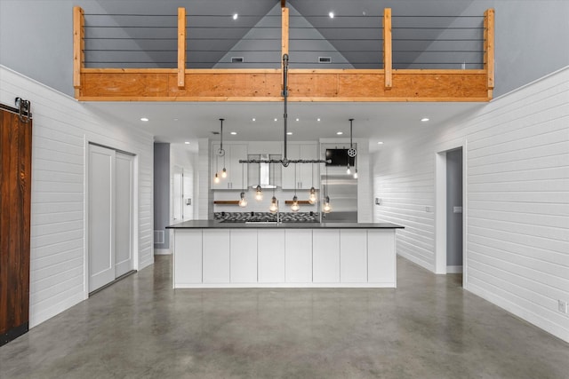 kitchen with concrete floors, dark countertops, and white cabinets