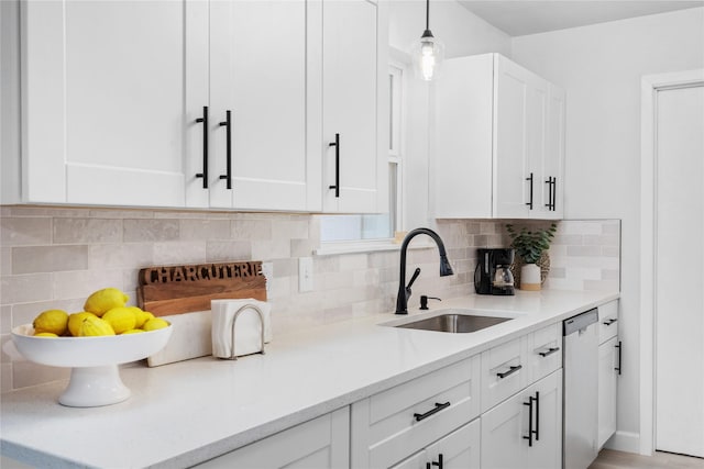 kitchen featuring dishwasher, white cabinetry, light countertops, and a sink