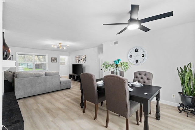 dining room featuring a fireplace, visible vents, a ceiling fan, light wood-type flooring, and baseboards