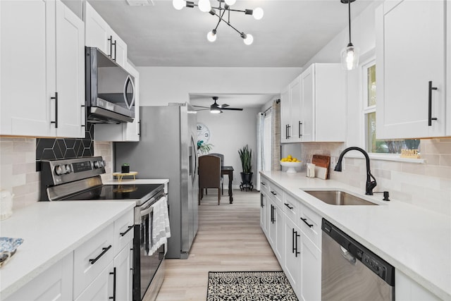 kitchen with white cabinets, appliances with stainless steel finishes, light countertops, and a sink