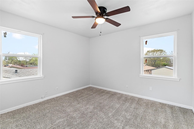 carpeted spare room with ceiling fan and baseboards