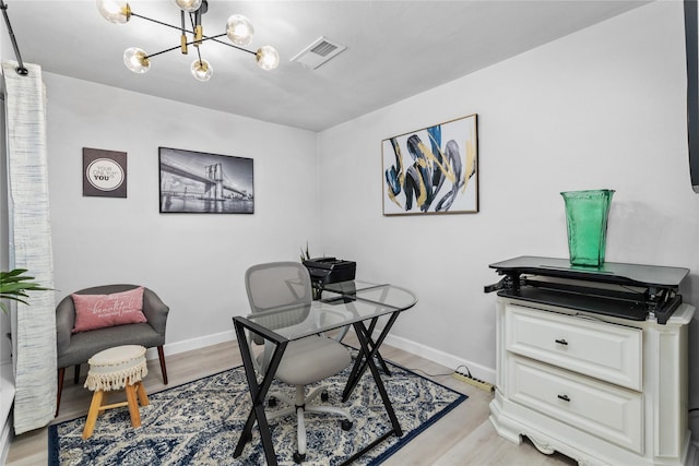 office area featuring baseboards, light wood finished floors, visible vents, and a notable chandelier