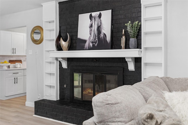 interior details featuring built in shelves, wood finished floors, baseboards, a brick fireplace, and backsplash