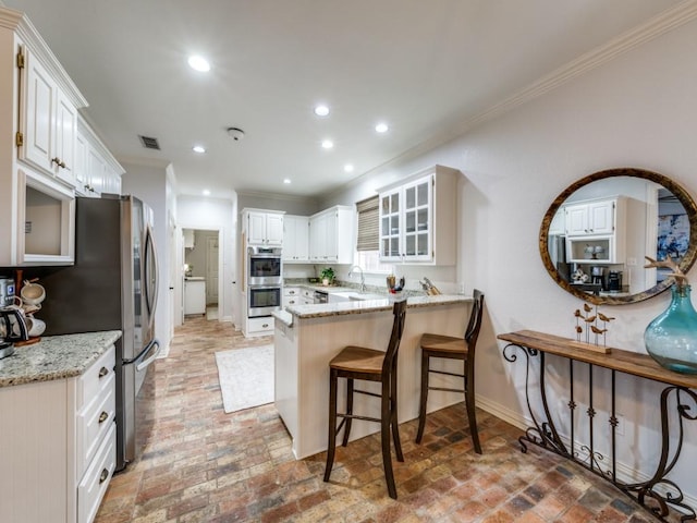 kitchen with a peninsula, double oven, visible vents, and recessed lighting