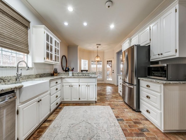 kitchen with brick floor, stainless steel appliances, ornamental molding, white cabinets, and a peninsula