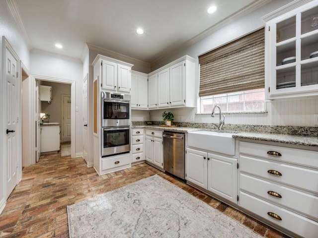 kitchen with appliances with stainless steel finishes, brick floor, crown molding, a sink, and recessed lighting