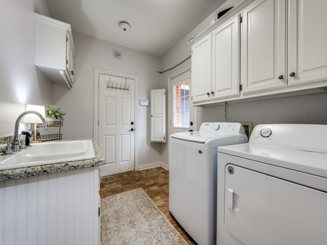 washroom with separate washer and dryer, a sink, cabinet space, and baseboards