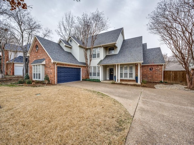 traditional-style house featuring concrete driveway, roof with shingles, an attached garage, a front lawn, and brick siding