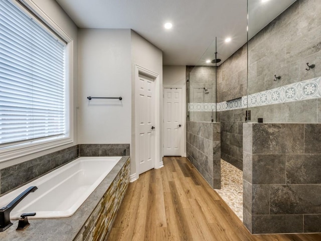 bathroom featuring recessed lighting, wood finished floors, a garden tub, and a walk in shower