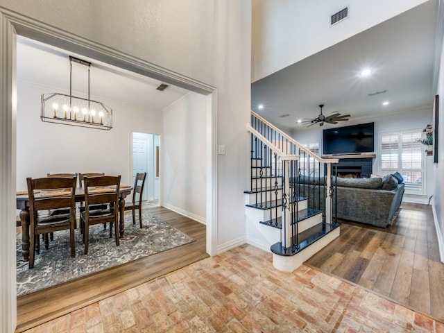 dining area featuring a fireplace, baseboards, crown molding, and wood finished floors