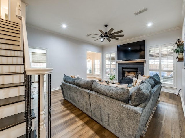 living room featuring crown molding, stairs, visible vents, and wood finished floors