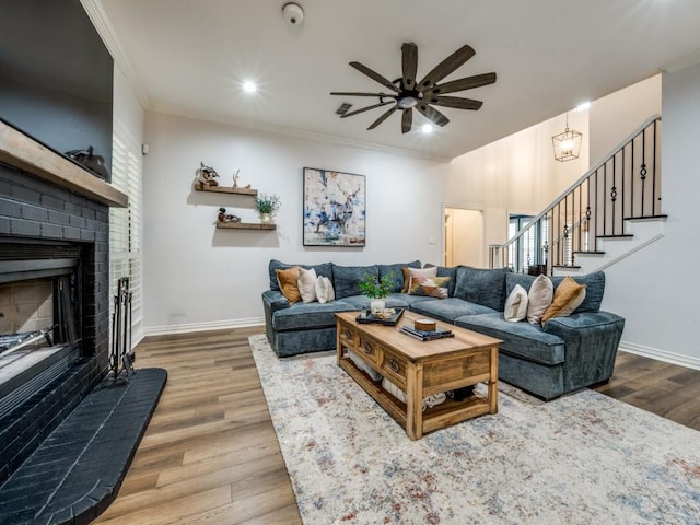 living room featuring ornamental molding, stairway, a brick fireplace, and wood finished floors