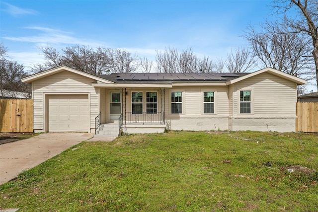 view of front of home featuring a garage, driveway, fence, roof mounted solar panels, and a front lawn