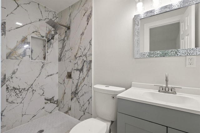 bathroom with toilet, a marble finish shower, and vanity