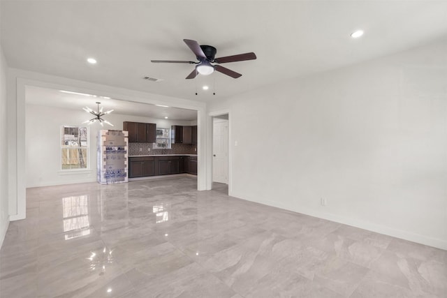 unfurnished living room featuring ceiling fan with notable chandelier, marble finish floor, recessed lighting, and baseboards