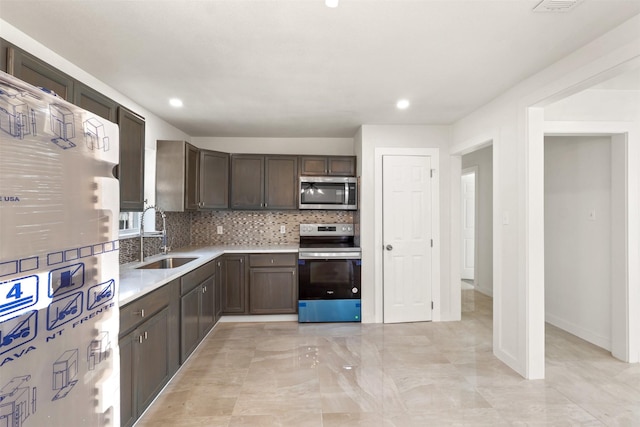 kitchen with dark brown cabinetry, stainless steel appliances, a sink, light countertops, and tasteful backsplash