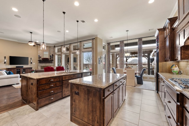 kitchen with a kitchen island with sink, a sink, visible vents, open floor plan, and backsplash