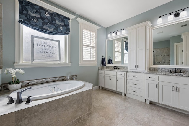 full bath with a bath, double vanity, a tile shower, and a sink