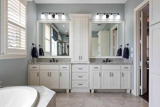 full bath featuring double vanity, a garden tub, visible vents, and a sink