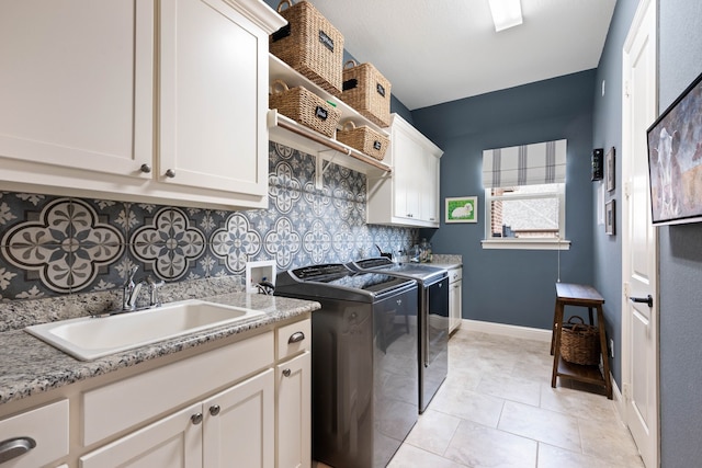 clothes washing area featuring washing machine and clothes dryer, light tile patterned floors, cabinet space, a sink, and baseboards