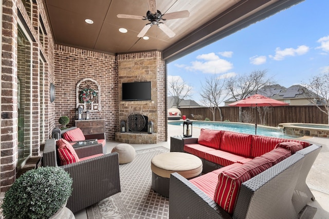 view of patio featuring a pool with connected hot tub, a fenced backyard, ceiling fan, and an outdoor living space with a fireplace