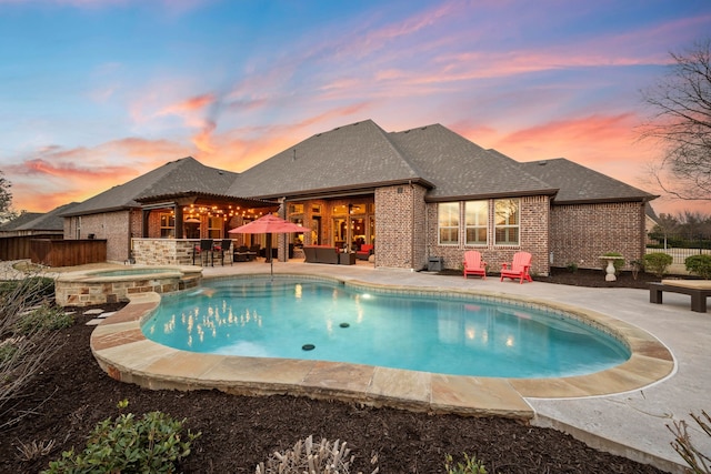 view of swimming pool featuring a patio area, a pool with connected hot tub, and fence