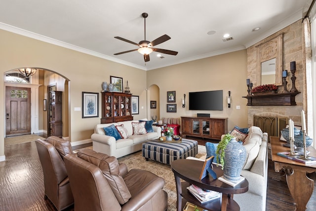 living area featuring arched walkways, visible vents, ornamental molding, wood finished floors, and baseboards