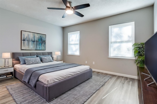 bedroom with a ceiling fan, a textured ceiling, baseboards, and wood finished floors