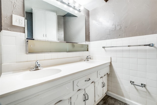 full bathroom with double vanity, a sink, and tile walls