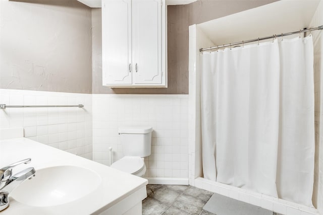 full bath with tile walls, a sink, a shower stall, and toilet