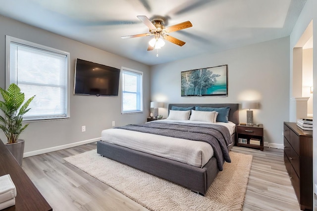 bedroom featuring light wood finished floors, a ceiling fan, and baseboards