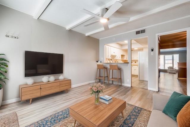 living area with beamed ceiling, wood finished floors, ceiling fan, and baseboards