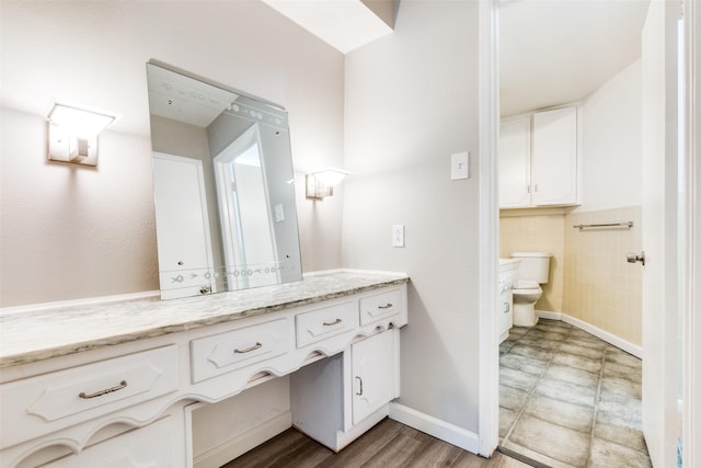 bathroom with baseboards, vanity, and toilet