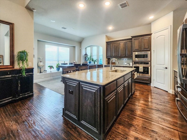 kitchen with stainless steel appliances, dark wood-style flooring, visible vents, and a sink