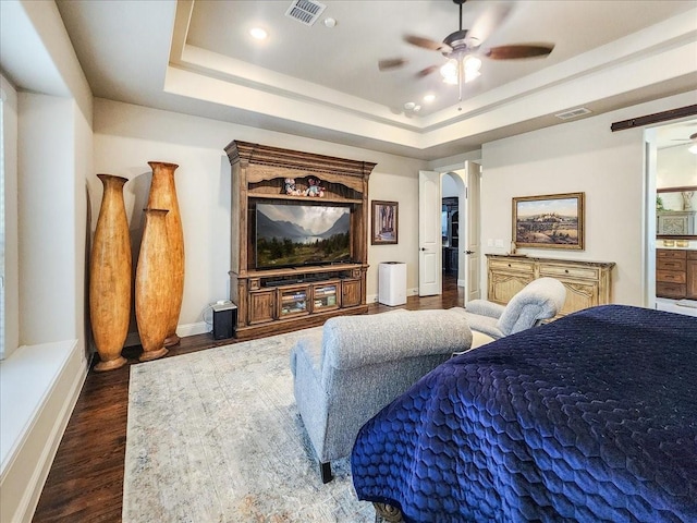 bedroom with arched walkways, a raised ceiling, and visible vents