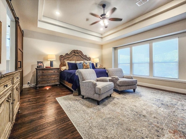 bedroom featuring dark wood-type flooring, a ceiling fan, visible vents, baseboards, and a raised ceiling