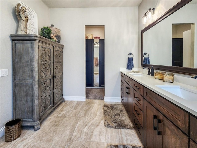 bathroom with double vanity, a sink, and baseboards