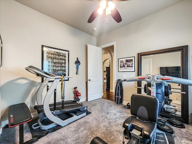 workout area featuring carpet floors, baseboards, arched walkways, and a ceiling fan