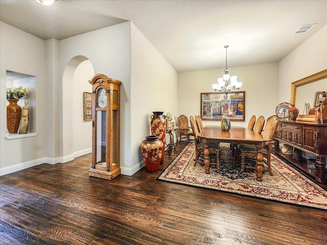 dining space featuring arched walkways, wood finished floors, visible vents, and a chandelier